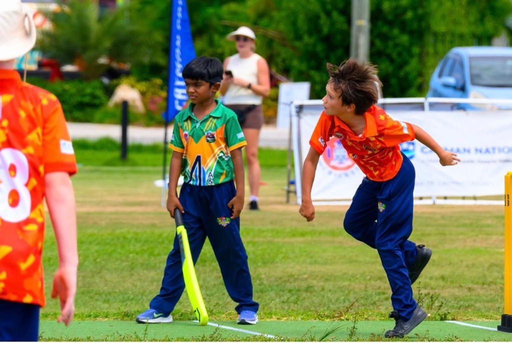 Junior bowler in orange jersey delivery stride