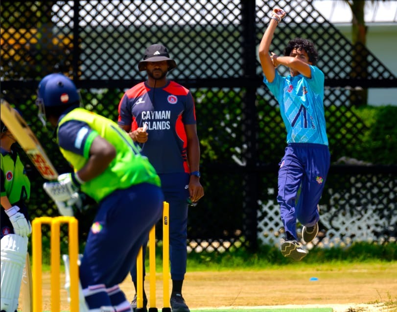 Young pace prospect leaping high in bowling delivery stride with coach